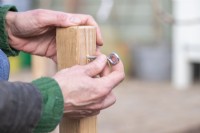 Woman screwing eyelet screws into the top of the wooden post