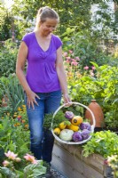 Woman with harvested vegetables - kohlrabi and courgettes.