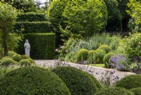Clipped buxus balls and mixed borders in The South Garden at Morton Hall with a classical statue in the background.
