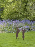 Hare ornaments in lawn in front of bluebells