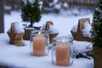 Table arrangement of two candles in a lantern snowed in