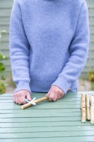 Woman whittling a birch stick so that it has a flat face at one end