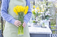 Woman holding a glass vase full of daffodils