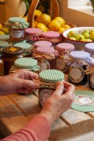 Applying gingham tops to jars of preserves and tying with rafia