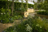 Herbaceous plants around the entrance to the meeting and kitchen area of the London Square Community Garden, a sanctuary garden designed by James Smith at the RHS Chelsea Flower Show 2023.