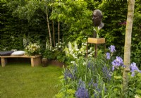 A bronze bust of King Charles III surrounded by borders of Iris 'Jane Philips', Camassia caerulea, Lupinus 'Polar Princess', Digitalis purpurea 'Alba' and Viburnum kilimanjaro in A Garden of Royal Reflection designed by Dave Green.