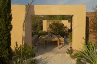 An outdoor dining area surrounded by Mediterranean plants in the Hamptons Mediterranean Garden, a sanctuary garden designed by Filippo Dester at the RHS Chelsea Flower Show 2023