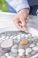 Woman placing stones in a pattern on the grout