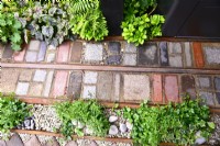 Mosaic path made of various  reclaimed natural materials with plants.
Designer: Nicola Haines, Citroen Power of One at Bord Bia Bloom Dublin 2023. 