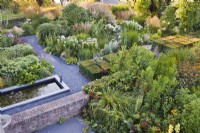 View acros the garden with white border, hot border, gravel paths and rectangular pond.