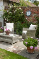 Patio in enclosed garden with ratan chairs and coffee table, planted containers and climbing Rose - Open Gardens Day, Easton, Suffolk