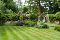 View across large striped lawn to borders, shrubs, pergola and garden building beyond - Open Gardens Day, Easton, Suffolk