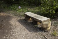 A rustic homemade wooden bench beside a path. Marwood Hill gardens, Devon