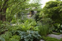 A tranquil woodland garden planted with specimen trees and shade-loving herbaceous plants surrounds a neo-classical temple.