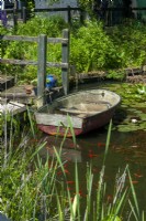 Boat on garden pond with rustic steps and handrail leading to it - Open Gardens Day, Shelfanger, Norfolk
