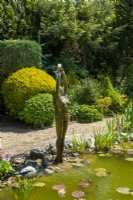 Water feature of naked lady beside pool against backgound border of trees and shrubs - Open Gardens Day, Shelfanger, Norfolk