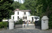 Owners of Villa Sprezzatura welcoming near the black iron gate and villa in the background.