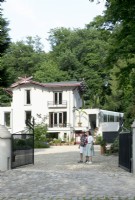 Owners of Villa Sprezzatura welcoming near the black iron gate and villa in the background.
