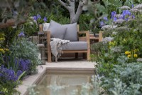 A chair overlooks a rill edged in grey-leaved artemisia, iris, umbellifers  and herbs. 
