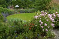Sweeping border of perennials, roses, shrubs and trees around lower circular lawn with steps leading down to it - Open Gardens Day, Tuddenham, Suffolk