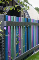 A picket fence built from reclaimed timber is painted in bright colours, a playful way of upcycling waste materials.