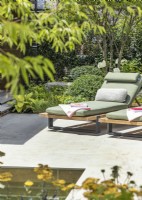 Terrace garden with smooth paved surface and sun lounger, summer July