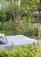 Day bed on terrace surrounded by beds of perennials and shrubs, summer July