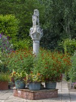 The Scottish Sundial and metal containers with mixed flowers  Old Vicarage Gardens  East Ruston Norfolk July Summer