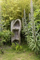 Wood carving surrounded by the spires of Echium pininana in a Cornish garden in May