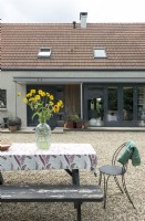 Front door. Picnic table on the gravel surface with colourful styling.The outdoor colourful decorated table with flowers from the garden
