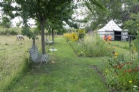 Long wild flower border near classic table and bench. Sheeps in the orchard. Arabic tent in the garden.