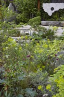 The Samaritans Listening Garden. Designer: Darren Hawkes. Chelsea Flower Show 2023. A garden of salvaged materials and suspended concrete panels. Summer. May.
View over mixed planting to a garden of salvaged materials and suspended concrete panel.