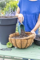 Woman filling both the large container and hanging basket with compost