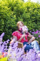Woman smelling sweet peas while relaxing in garden