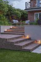 Recessed lighting for brick steps leading up to terrace with furniture