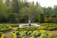A statue atop a fountain surrounded by Taxus baccata topiary in the Fountain Garden in the Crathes Castle Walled Garden.