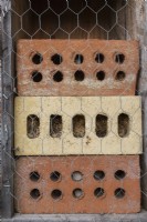 Bug hotel made from clay bricks with drilled holes for insects to hide and hibernate.