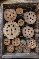 Bug hotel made from cut logs with drilled holes for insects to hide and hibernate.