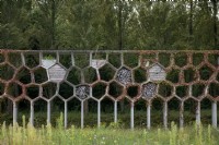 Garden feature Honeycomb pergola covered in ivy Maximapark The Netherlands. 
Old wood placed within the honeycombs to provide habitat for insects. 