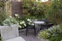 Corner seating area with raised bed and contemporary wood boundary fence with metal screen.