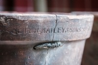 Details of vintage terracotta plant pot showing the makers mark and crack repaired with metal strap