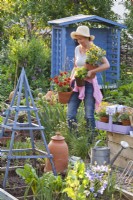 Women carrying potted zinnias ready for planting in the kitchen garden to attract beneficial wildlife.