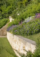 Stone retaining wall with a bed of flowering perennials, August summer