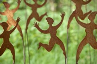 Display of garden ornaments of dancing ladies made from rusting corten steel at Derry Watkins Special Plants Nursery