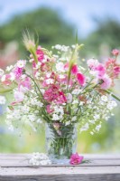 Bouquet of flowers containing Gypsophila elegans 'Covent Garden', Centaurea cyanus - pink, Delphinium 'Salmon Spire', Hordeum jubatum and Lathyrus 'Painted Lady' - Sweet Peas in glass vase