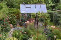 Seedpod garden at Falkners Cottage, Wiltshire in September with Seed Pod by Ted Edley surrounded by planting of orange and purple