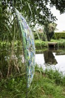 Glass mosaic sculpture, Sail by Katie Green, in a country garden

