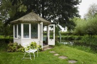 Summerhouse on an island in a large pond in a country garden in September