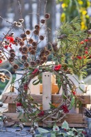 Winter display with wreath of mistletoe and guelder rose and bunches of pine, larch, pussy willow and guelder rose twigs in milk churns.