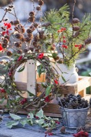 Winter display with wreath of mistletoe and guelder rose , pots with pine cones and bunches of pine, larch, pussy willow and guelder rose twigs in milk churns.